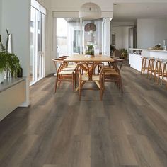 a dining room with wood flooring and white walls in the background is an open kitchen