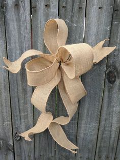 a burlap bow hanging on a wooden fence