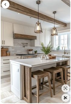 a kitchen island with stools in front of it and lights hanging from the ceiling