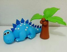 a blue toy dinosaur next to a small palm tree