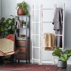 a room with a chair, potted plant and towel rack on the wall next to it