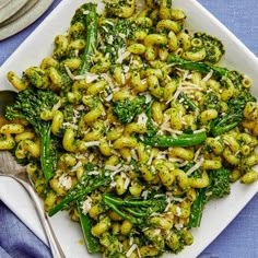 a white plate topped with pasta and broccoli covered in parmesan cheese