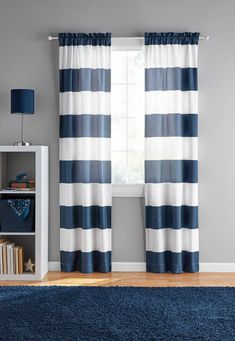 a blue and white striped curtain hanging in front of a window with bookshelf