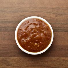 a white bowl filled with chili sauce on top of a wooden table