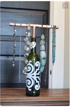 a wine bottle with beads hanging from it's side sitting on a wooden table