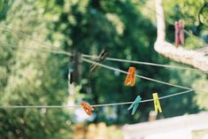 colorful clothes pins are hanging on a line in front of some trees and bushes,