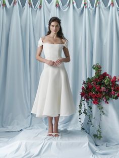 a woman in a white dress standing next to flowers