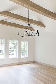 an empty room with three windows and a chandelier hanging from the rafters