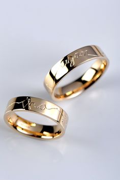 two gold wedding bands with the word love engraved on them, sitting next to each other