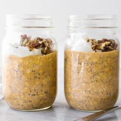 two jars filled with food sitting on top of a table next to a spoon and napkin