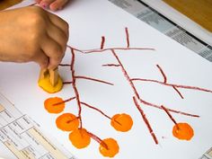 a child's hand is stamping an orange tree on a piece of paper