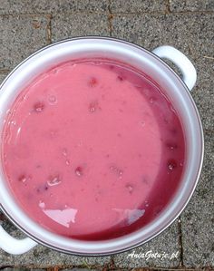 a pot filled with pink liquid sitting on top of a cement floor next to a sidewalk