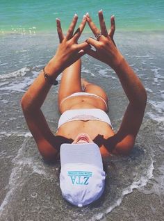 a woman laying on the beach with her hands in the air