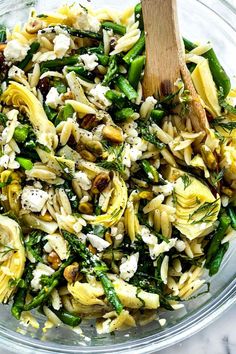 a glass bowl filled with pasta and vegetables