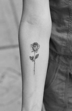 a black and white photo of a rose tattoo on the arm