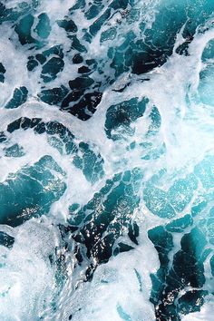 an aerial view of the ocean with waves crashing on it's rocks and foamy water