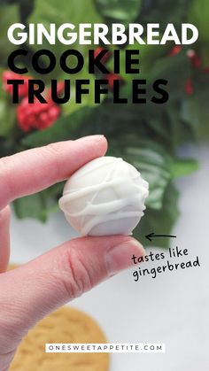 a hand holding a cookie truffles in front of some cookies and holly leaves