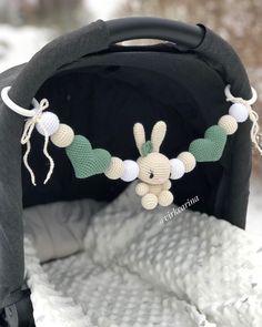 a crocheted bunny is hanging from the side of a stroller in the snow