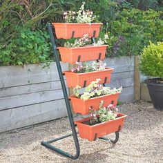 four orange plastic containers are stacked on top of each other with flowers in them and plants growing out of them