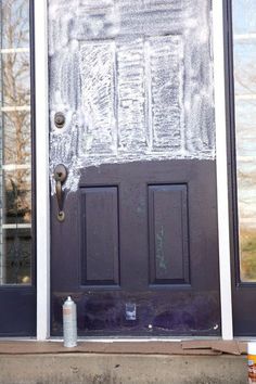 the front door is covered in frost and has two small cans of paint next to it