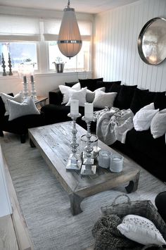 a living room filled with black couches next to a white coffee table and chandelier