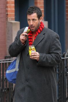 a man in a black coat and red scarf holding a bottle