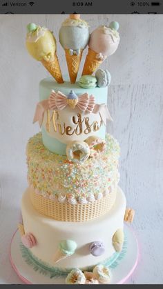 a three tiered cake with an ice cream cone and name on the top layer