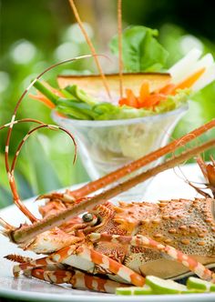 a plate with some lobsters on it and a bowl of vegetables in the background