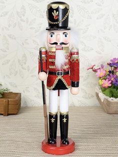 a nutcracker is standing on a table next to some flowers and a potted plant