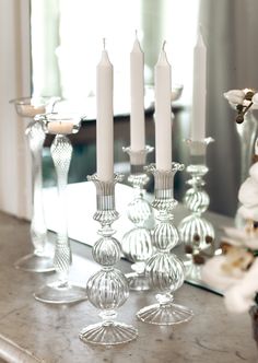 candles are lined up on a table with glass vases