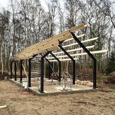 a wooden structure is being built in the middle of a field with trees behind it