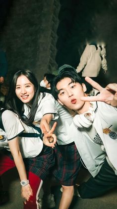 two young people posing for the camera with their hands in the air while wearing school uniforms