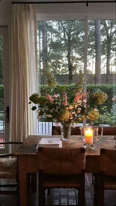 a dining room table with vases filled with flowers and candles on top of it