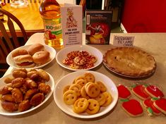 a table topped with plates of food and pie next to a bottle of apple cider