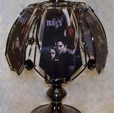 the twilight saga movie poster is attached to an umbrella shaped glass table lamp that sits on top of a marble surface