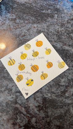 a piece of paper with bees on it sitting on top of a table next to a candle