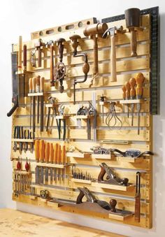 a wooden workbench with many tools hanging on it's wall and attached to the wall