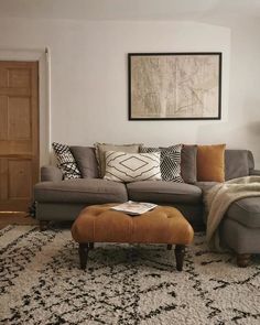 a living room with a couch, ottoman and rug on the floor in front of a door