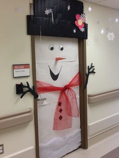 a snowman made out of toilet paper on the door to an office building with decorations around it