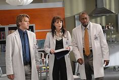 three people in lab coats are talking to each other on the set of grey's anatomy