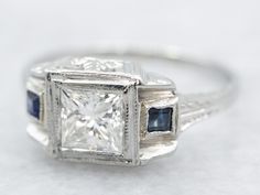 an antique diamond and sapphire engagement ring on a white surface with blue stones in the setting