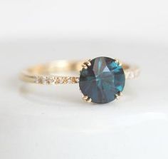 a close up of a ring with a blue stone in it on a white surface