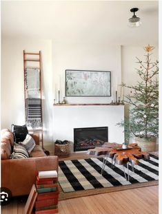 a living room filled with furniture and a christmas tree on top of a fireplace mantel