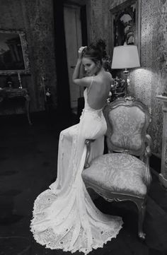 a woman in a wedding dress sitting on a chair next to a lamp and mirror