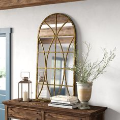 a wooden table topped with a vase filled with flowers next to a mirror on top of it