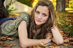 a beautiful young woman laying on top of leaves