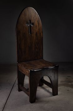 a wooden church chair with a cross on the back and seat, sitting in a dark room