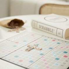 a scrabble board game sitting on top of a table next to a book