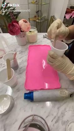 a person in white gloves is making something pink