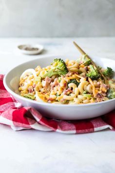 a white bowl filled with pasta and broccoli on top of a red and white towel